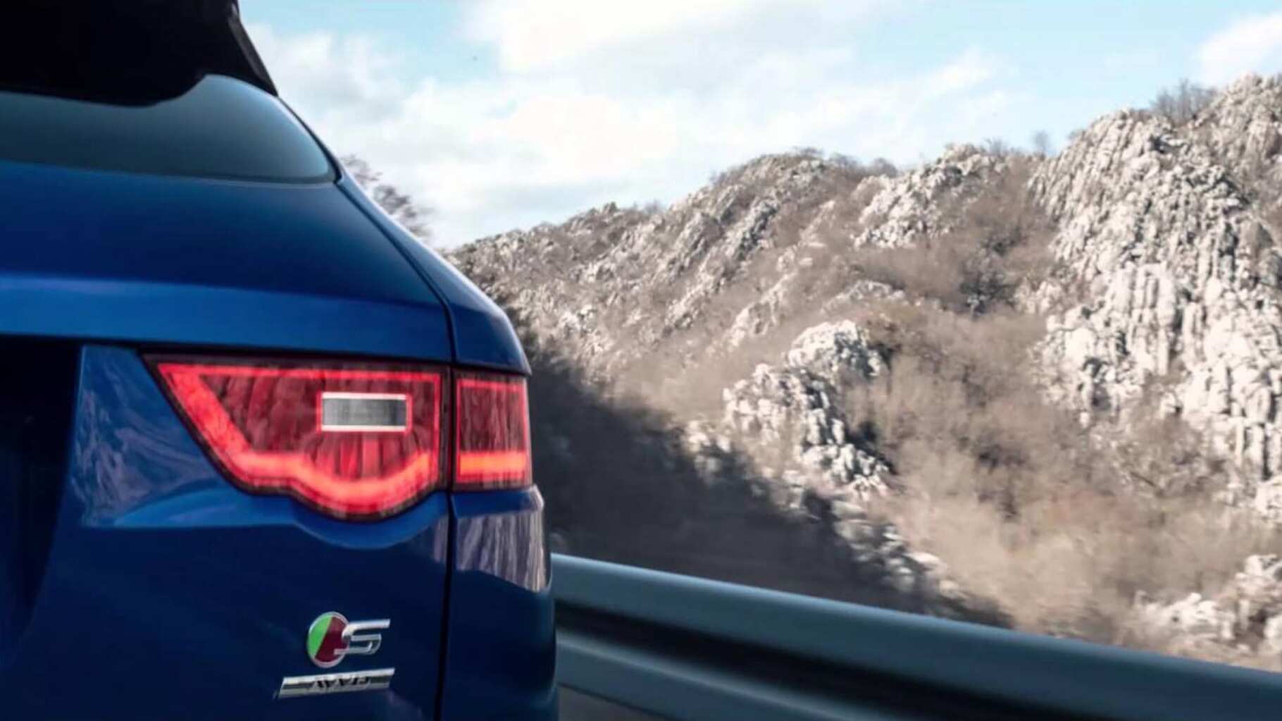 F-pace driving on a road by a mountain.